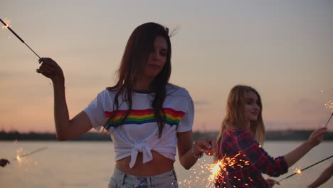 La-Bella-Mujer-De-Cintura-Desnuda-Baila-Con-Grandes-Luces-De-Bengala-En-La-Costa-Del-Río.-Esta-Es-Una-Agradable-Tarde-De-Verano-En-La-Fiesta-Al-Aire-Libre-Bajo-El-Atardecer-Rosado.